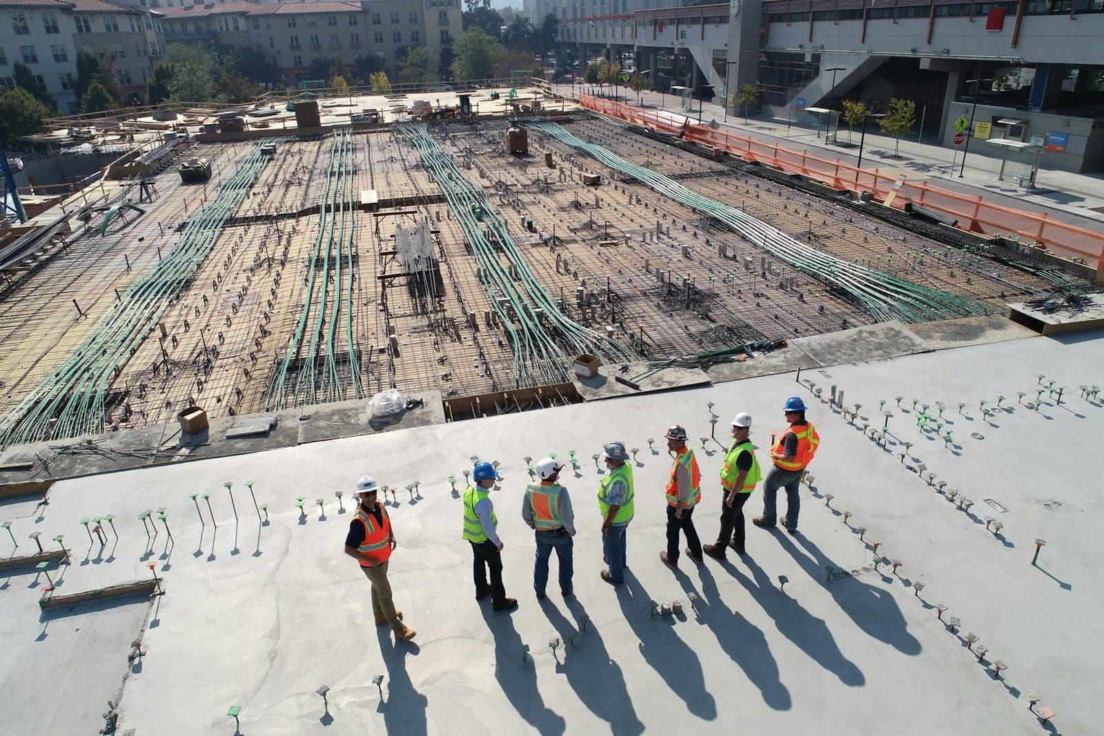 Engineers in safety vests surveying a large development site at foundation stage